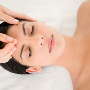 acupuncture to woman's forhead